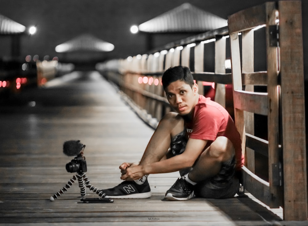 woman in red t-shirt sitting on wooden bridge