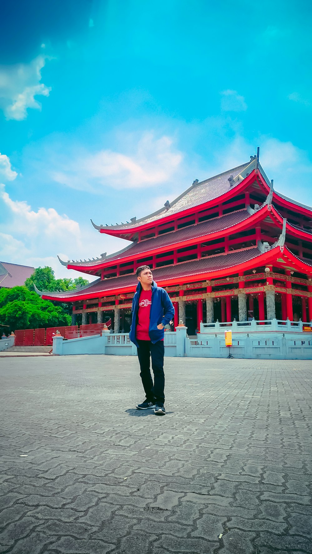 man in gray dress shirt and black pants standing near red temple during daytime