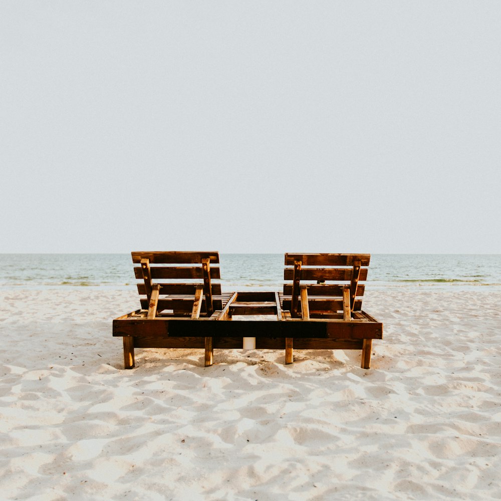 낮에는 하얀 모래 해변에 갈색 나무 의자