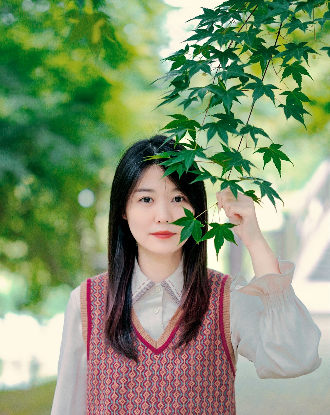 woman in white and red shirt holding green leaves