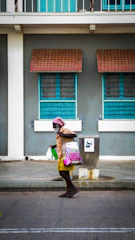 A friendly caregiver assisting an elderly woman with shopping bags in a sunny Rio de Janeiro street.