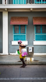 A friendly caregiver helping an elderly client carry shopping bags on a sunny street.