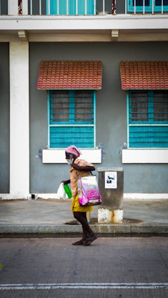 A friendly caregiver assisting an elderly woman with shopping bags in a sunny Rio de Janeiro street.