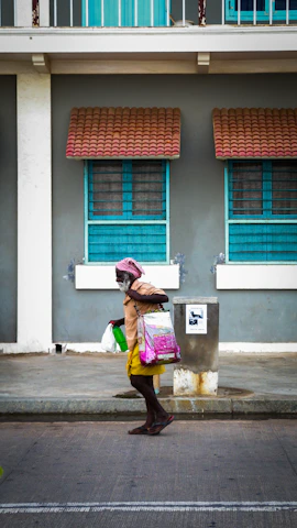 A kind companion helping an elderly woman with her shopping bags in a sunny neighborhood park.