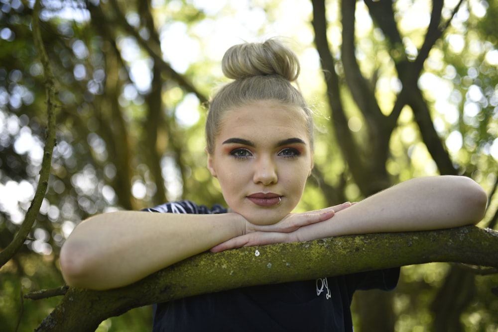 girl in blue and white stripe shirt leaning on tree during daytime