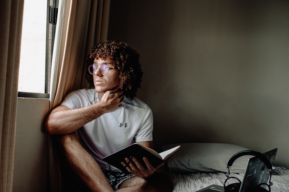 man in white polo shirt wearing black framed eyeglasses holding white tablet computer