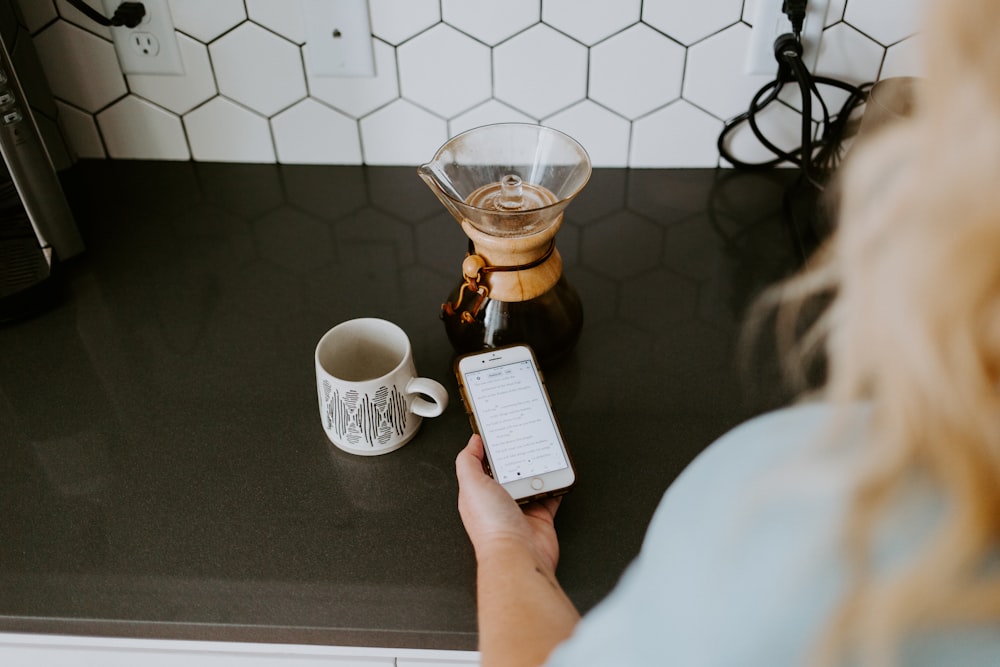 person holding white box near clear glass mug