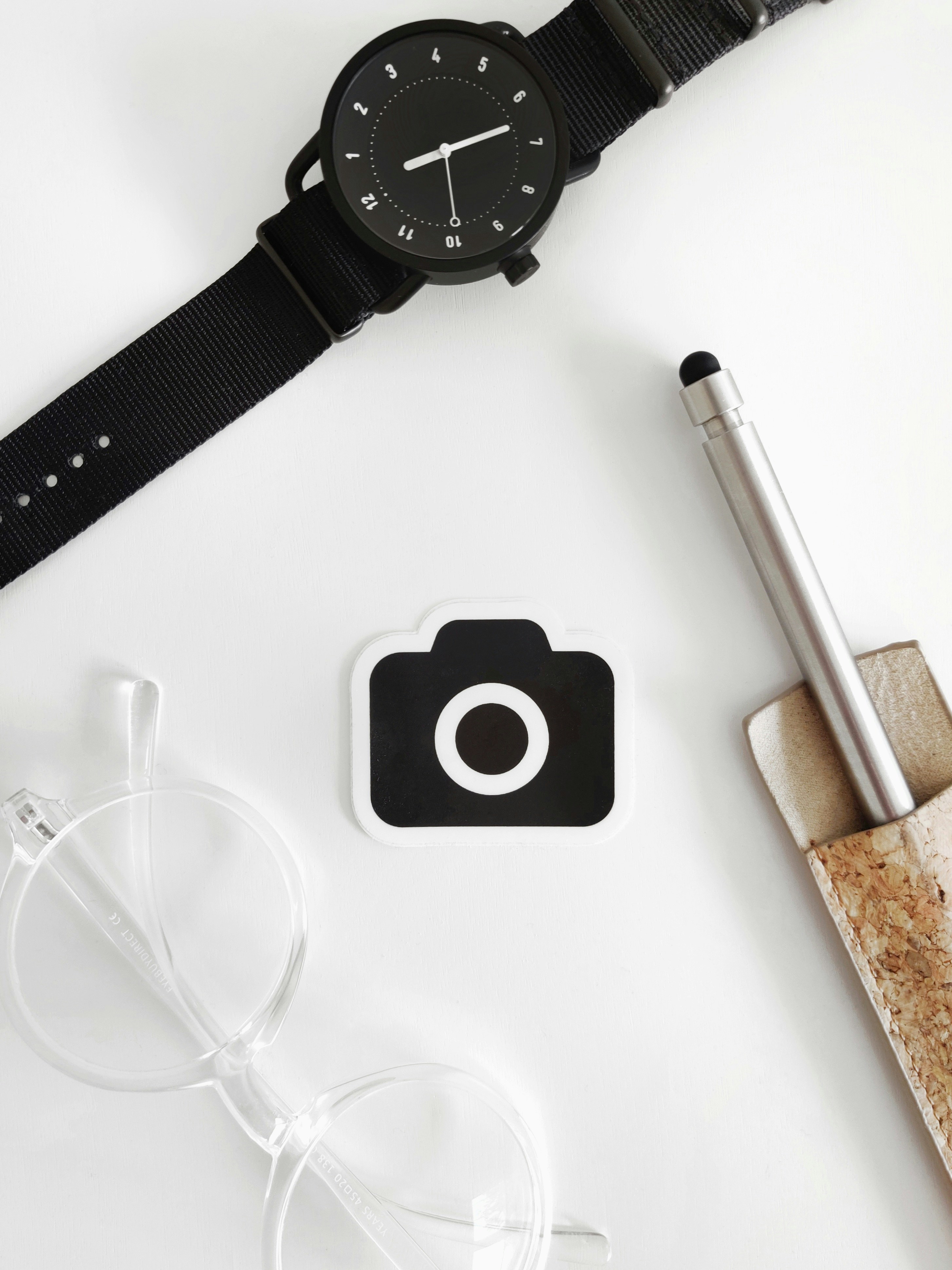 black round analog watch beside silver pen and white pen
