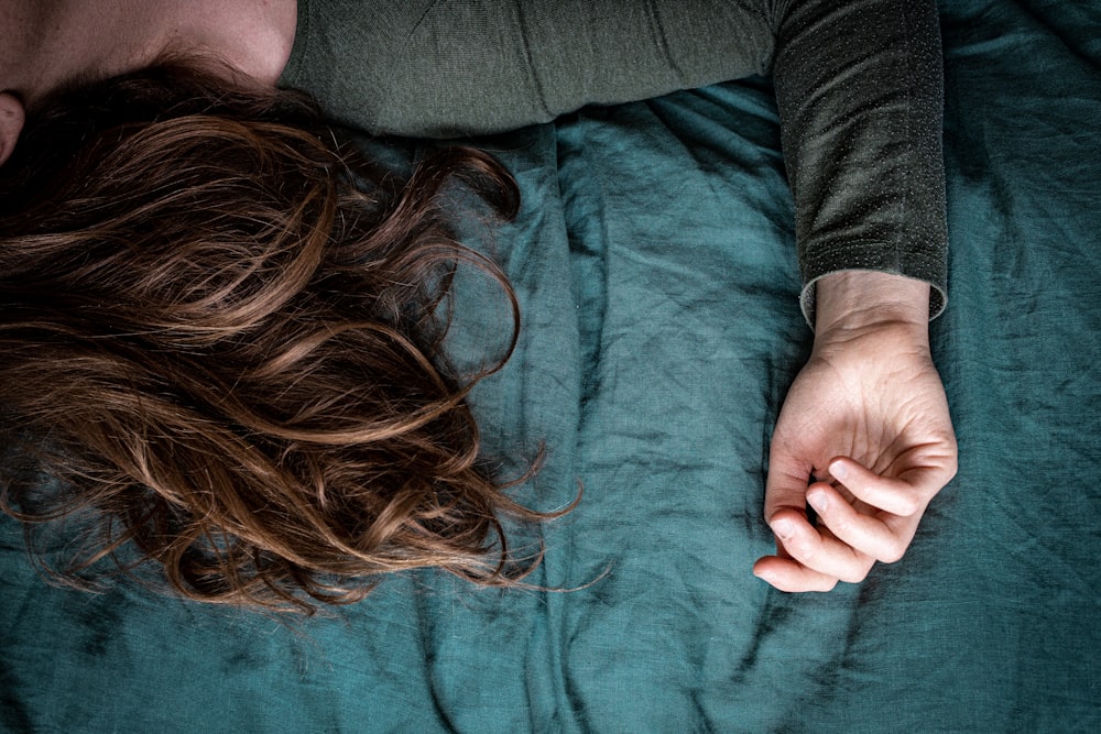 mujer en camisa gris de manga larga acostada sobre tela azul