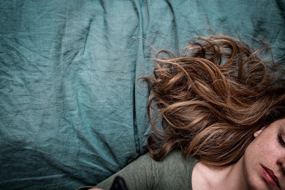 mujer con camisa gris acostada sobre tela azul