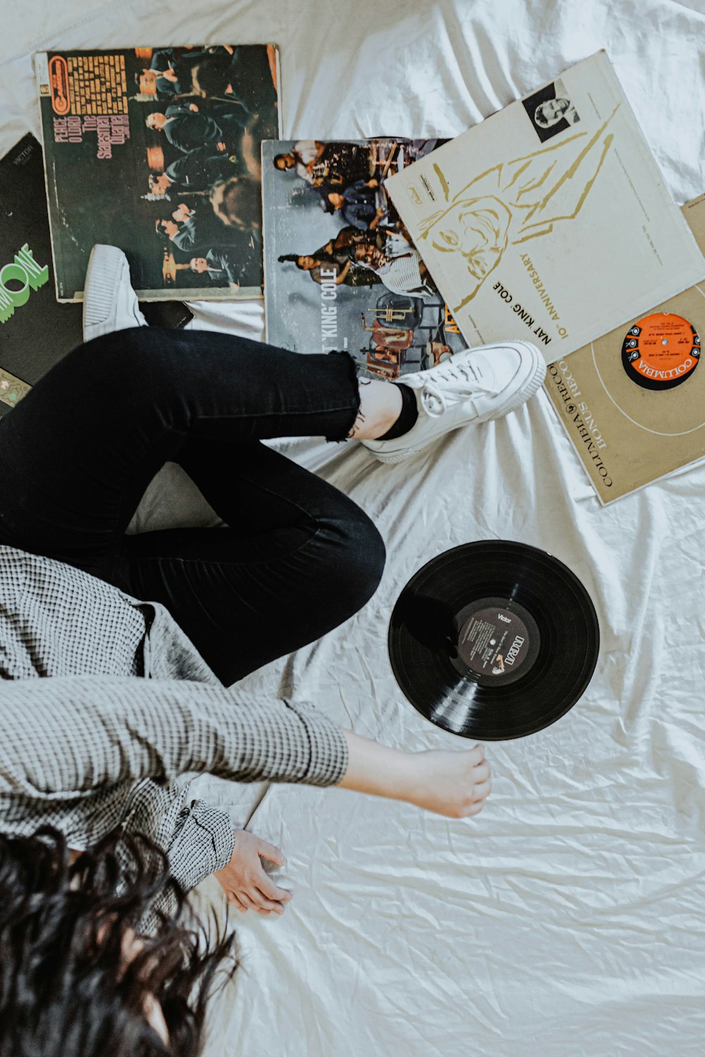 person in black pants sitting on white bed