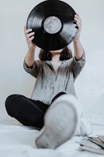 A cozy scene with a fan wearing a Ruby Mae Davenport branded scarf, holding a vinyl record.