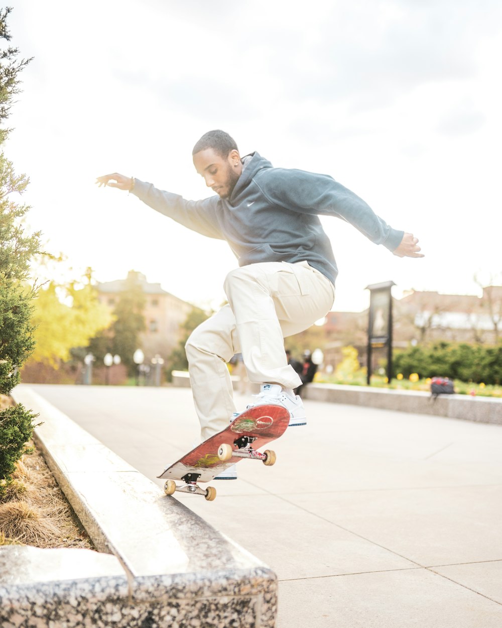 uomo in felpa con cappuccio grigia e pantaloni marroni che cavalcano lo skateboard durante il giorno