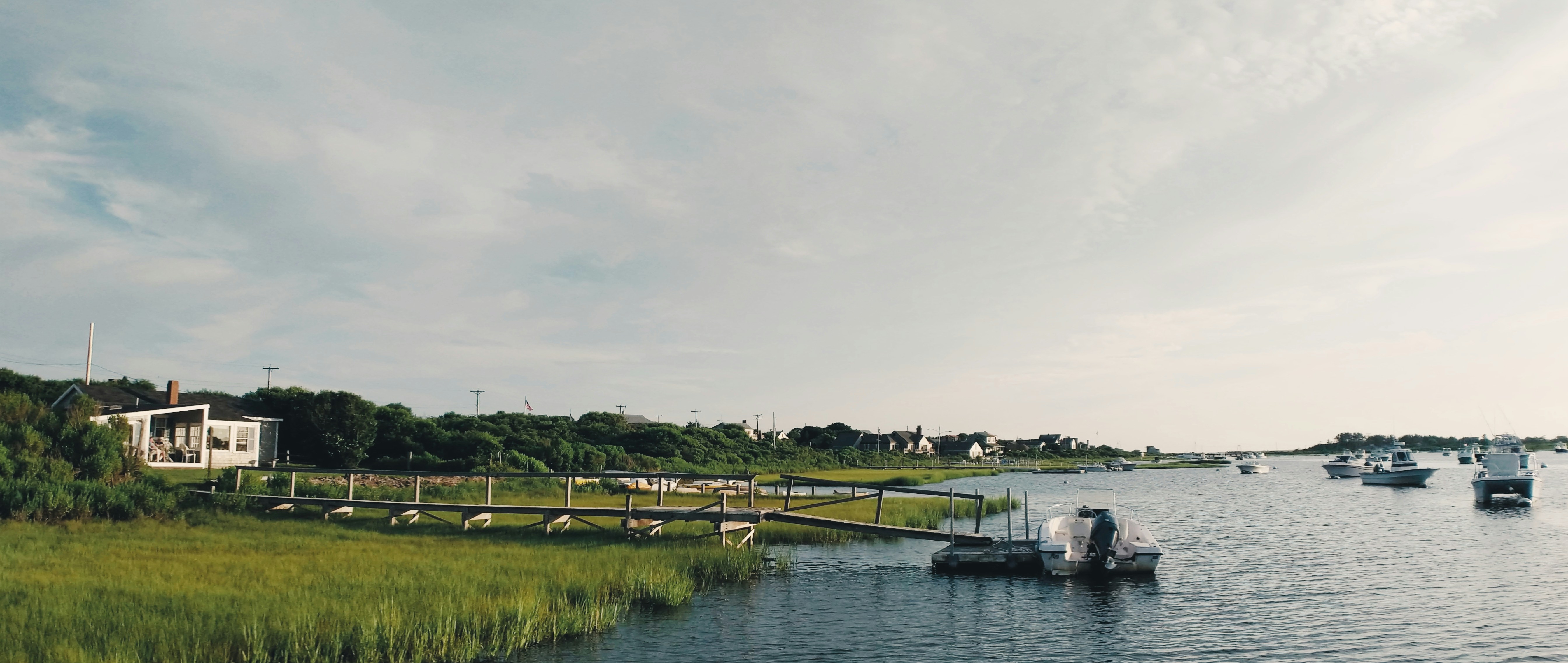 a body of water with boats floating on top of it, Nantucket harbor view with dock