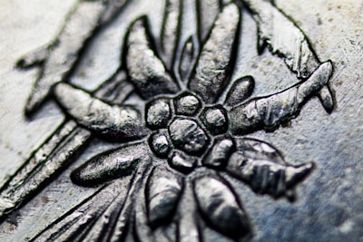 Close-up of a wooden plaque being laser engraved with a delicate floral design.