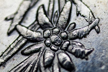 A close-up view of an intricate metal engraving depicting a floral pattern with detailed textures. The image highlights the craftsmanship involved in creating the piece.
