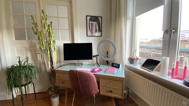 A cozy, modern home office with a clean desk and a vase of fresh flowers by the window.
