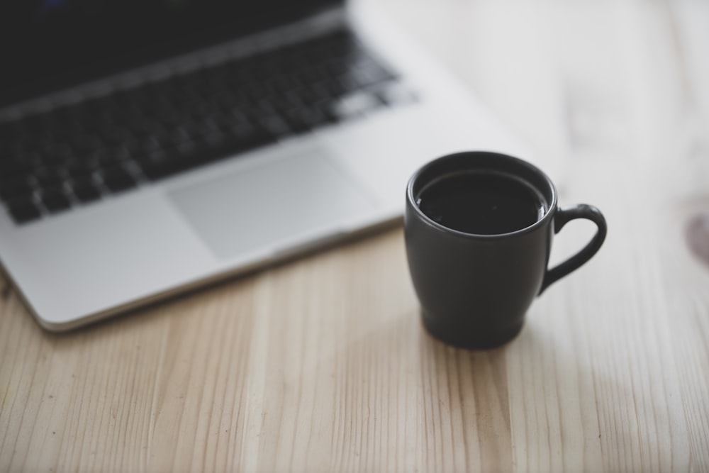 Mug en céramique noire à côté du MacBook Pro