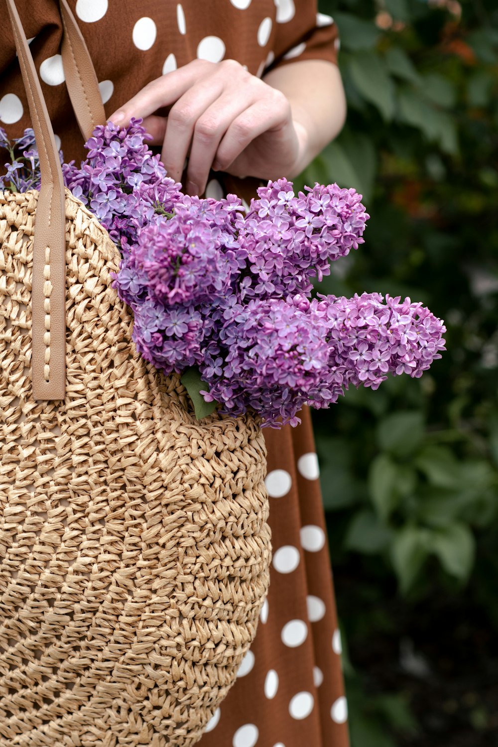 person holding brown woven basket with purple flowers