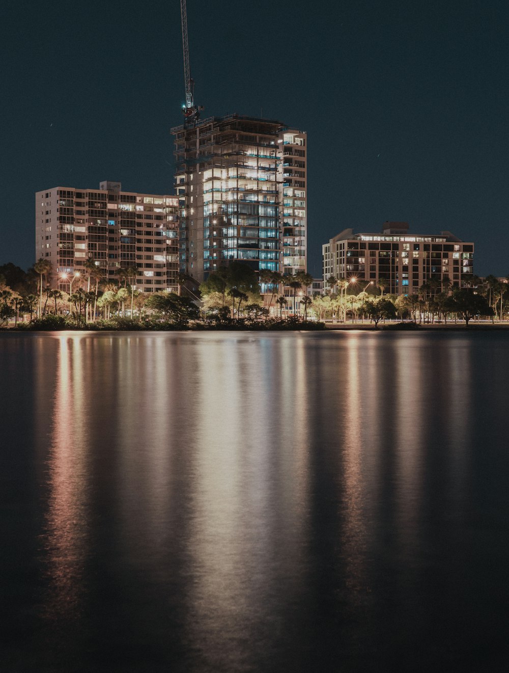 city skyline across body of water during night time
