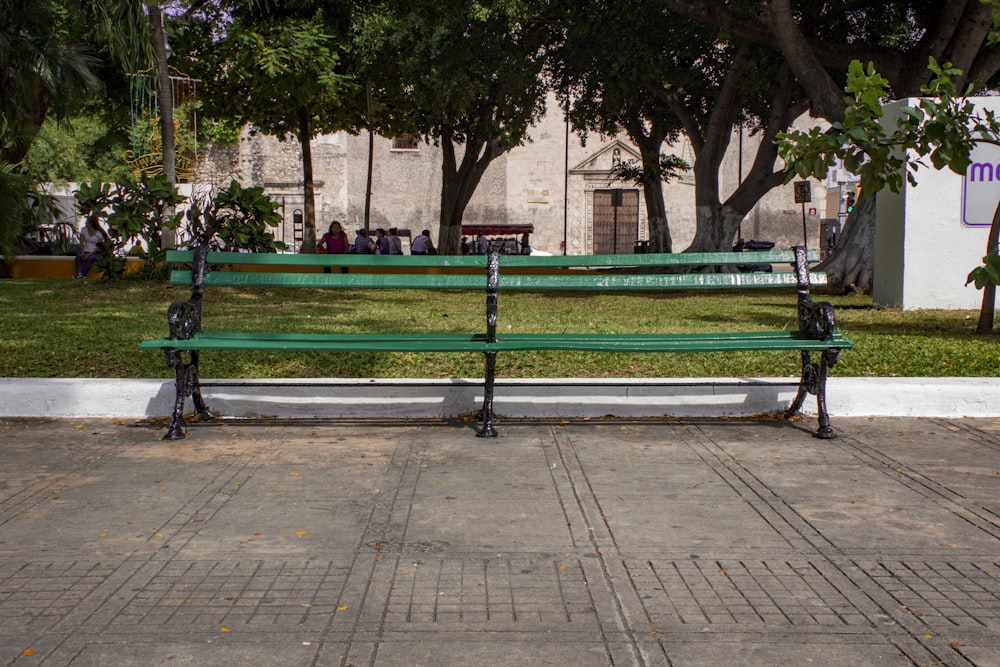 green metal bench near trees during daytime