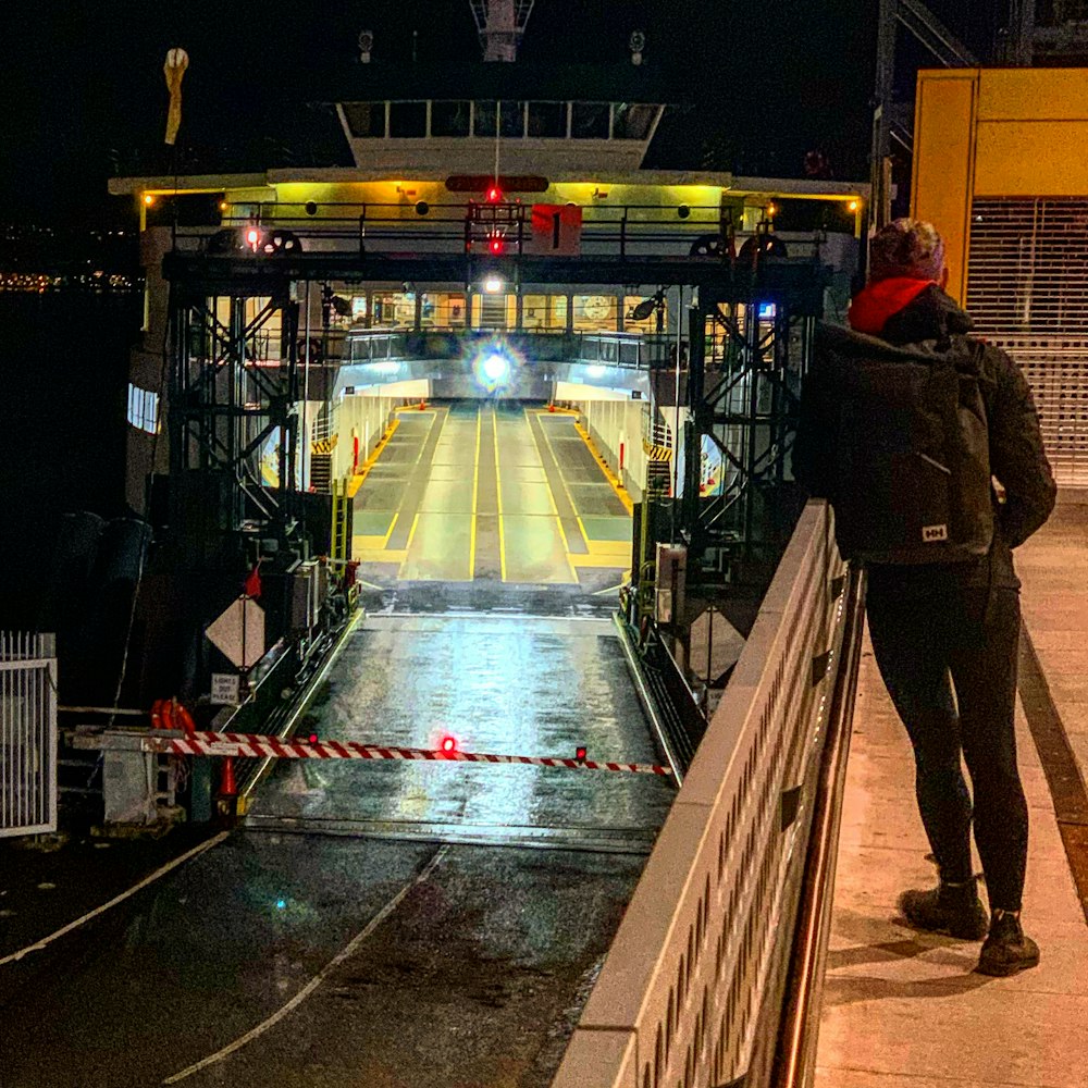 man in brown jacket standing on brown wooden dock during night time