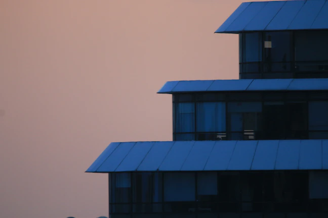 Evening view of the institute building lit with soft teal lights against a clear dusky sky.