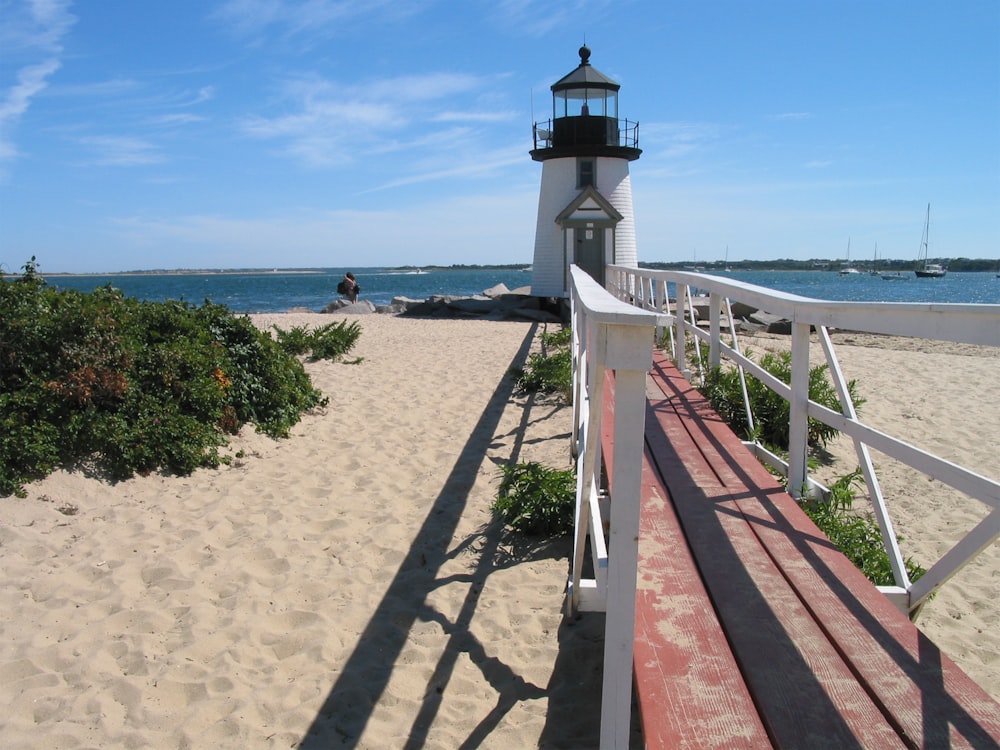 white and black lighthouse near body of water during daytime