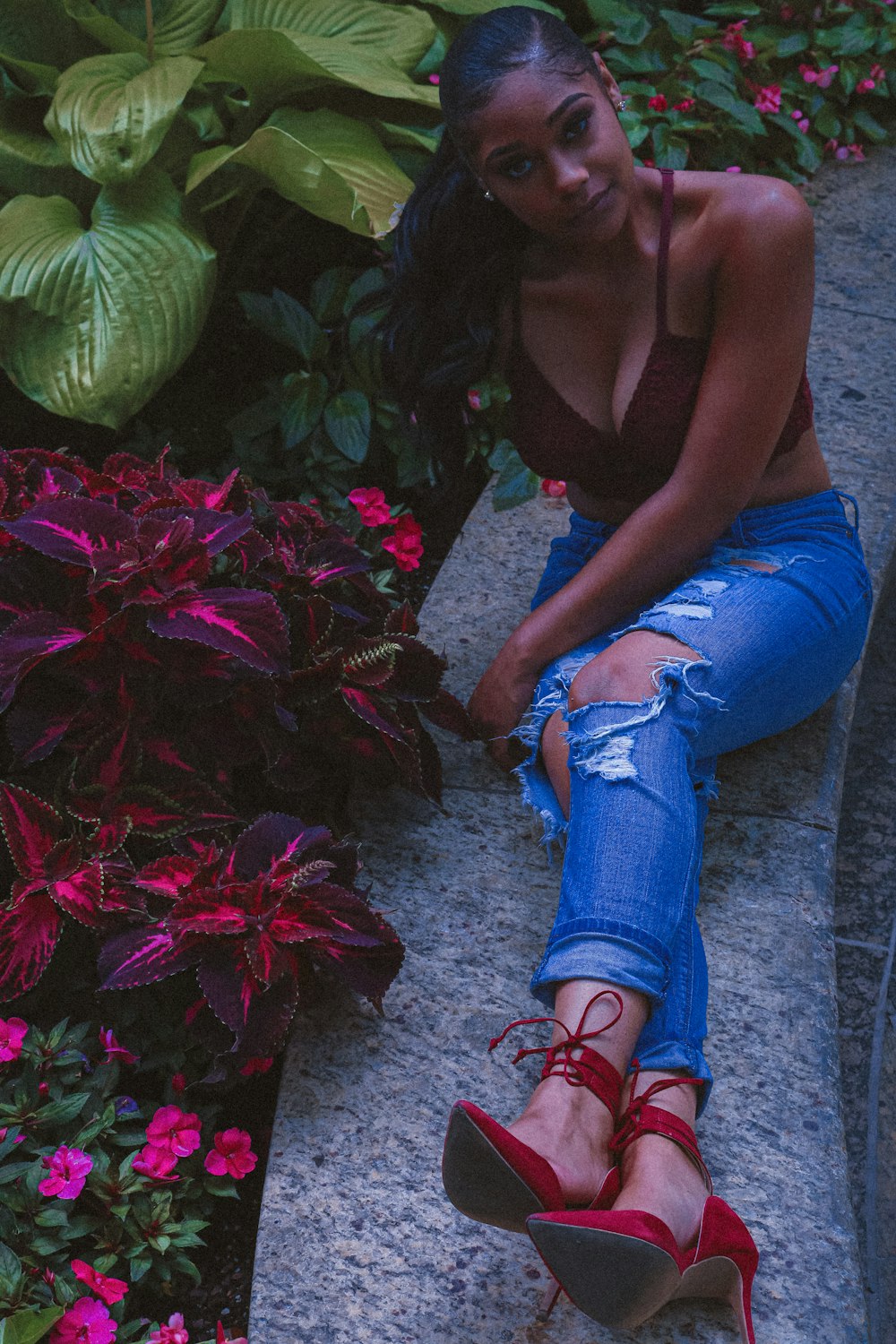 a woman sitting on the ground next to flowers