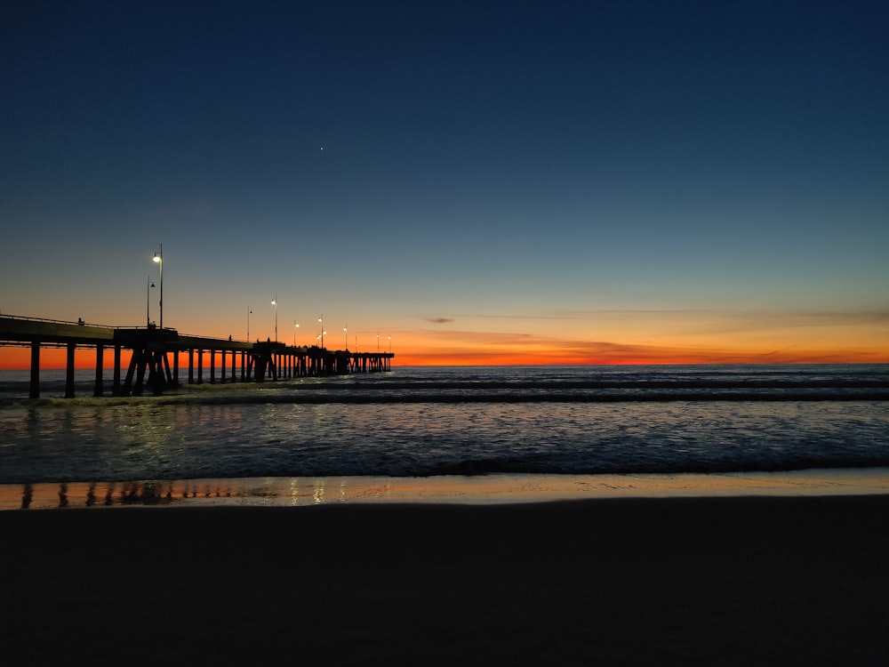 silhouette of bridge on sea during sunset