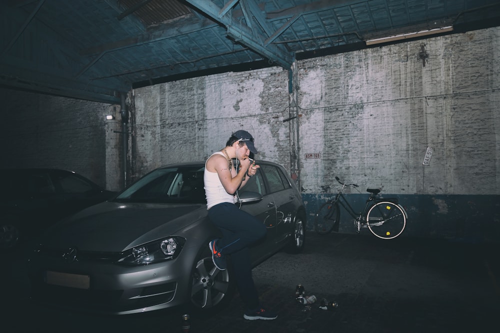 man in black t-shirt and black pants sitting on black car