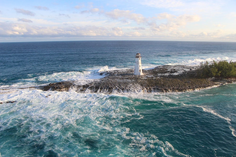 white lighthouse on brown rock formation on sea during daytime