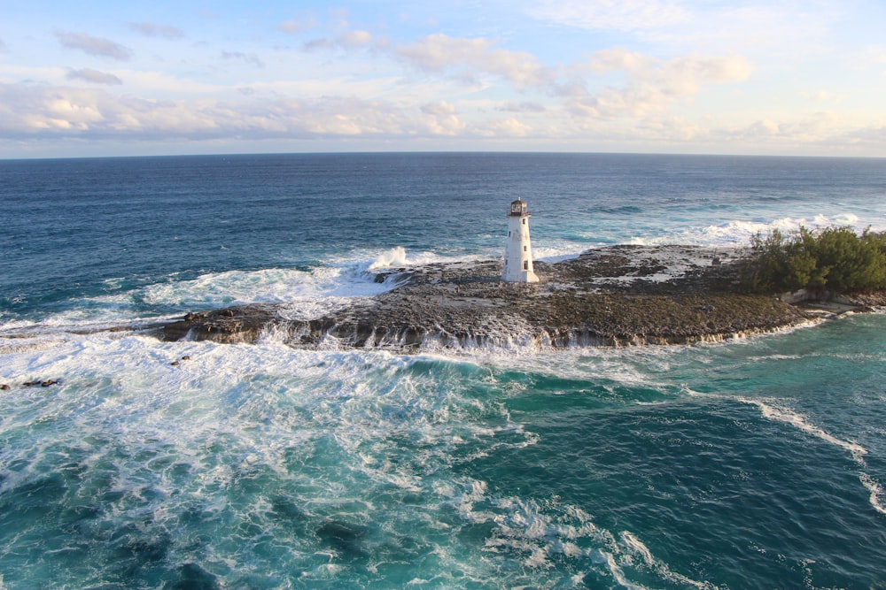 昼間の海上の茶色の岩層に白い灯台