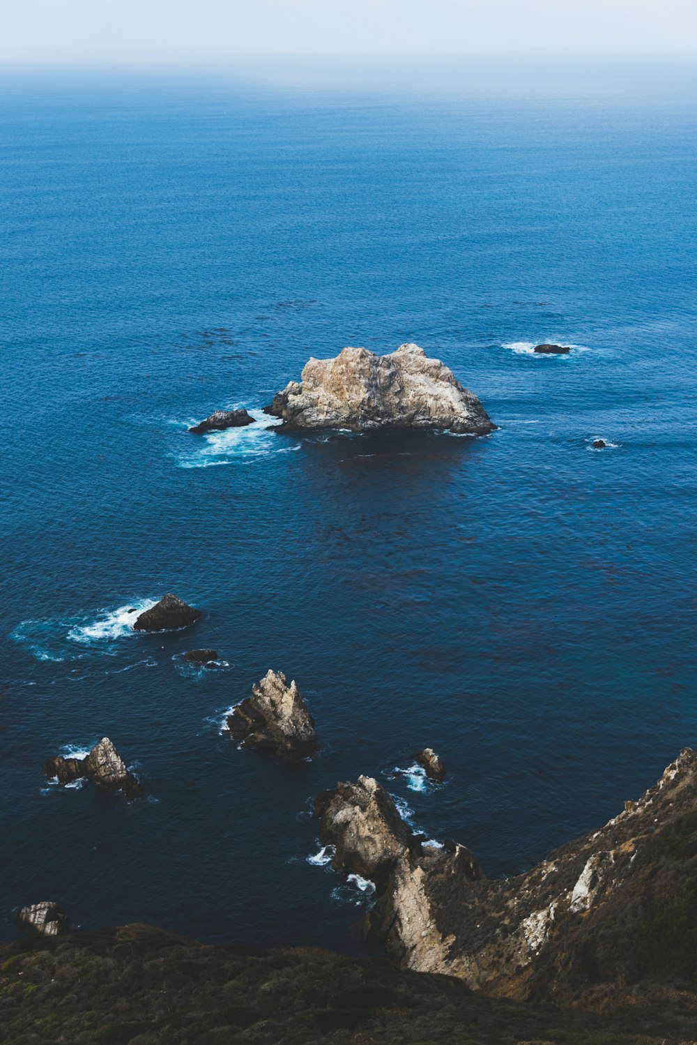 昼間の青い海に浮かぶ茶色の岩層