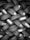 A tightly packed arrangement of new tires, each with distinct tread patterns and labels. The tires are stacked in an overlapping, lattice-like formation, creating an intricate visual texture.