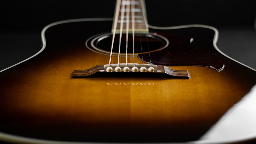 brown acoustic guitar on brown wooden table