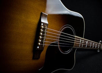 brown acoustic guitar on brown textile