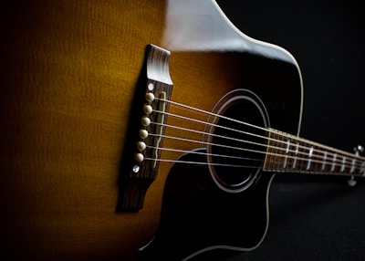 brown acoustic guitar on brown textile
