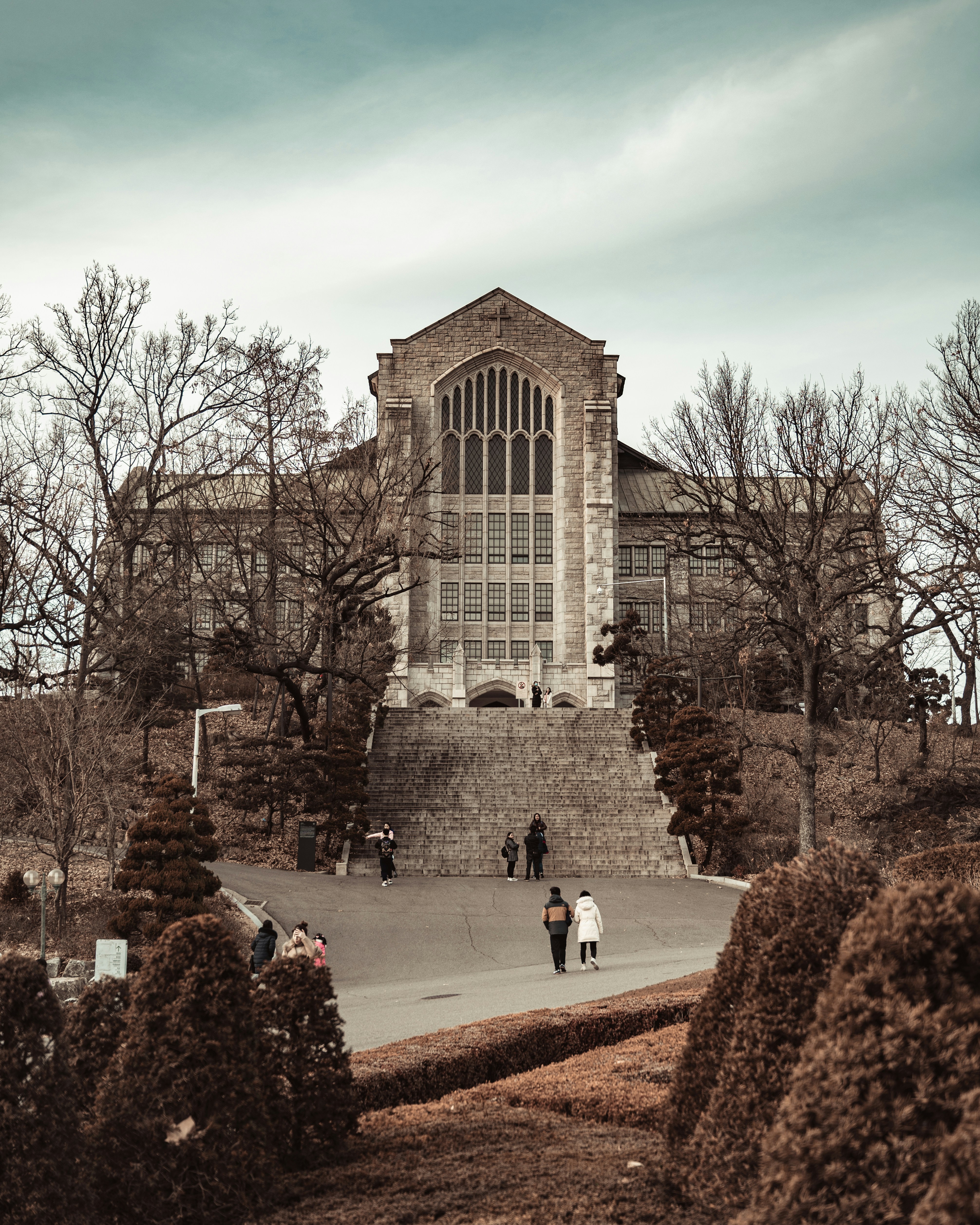 people walking on pathway near brown concrete building during daytime