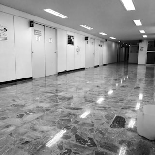 A hallway filled with identical doors labeled 'Meeting Room A' through 'Meeting Room Z', with employees wandering aimlessly.