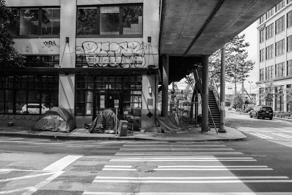 grayscale photo of man sitting on bench near building