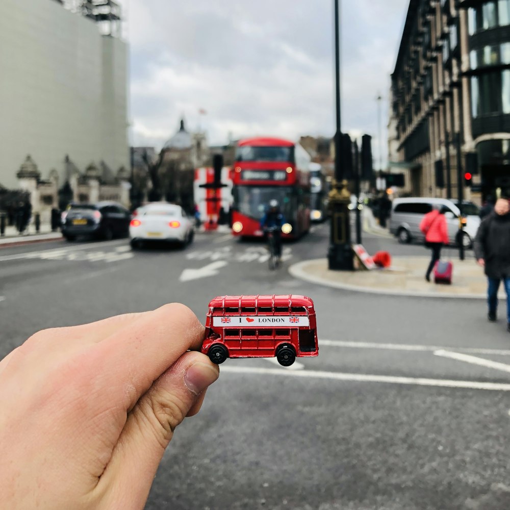 person holding red car on road during daytime