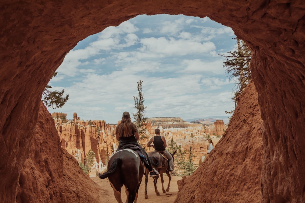 2 hombres montando a caballo en una formación rocosa marrón durante el día