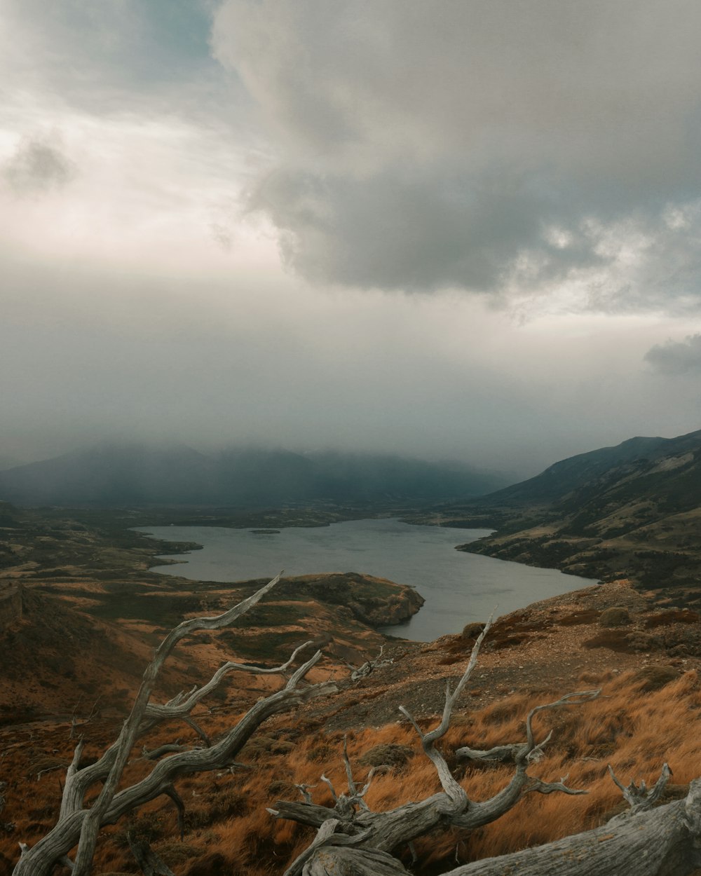 brown rocky mountain near body of water under cloudy sky during daytime