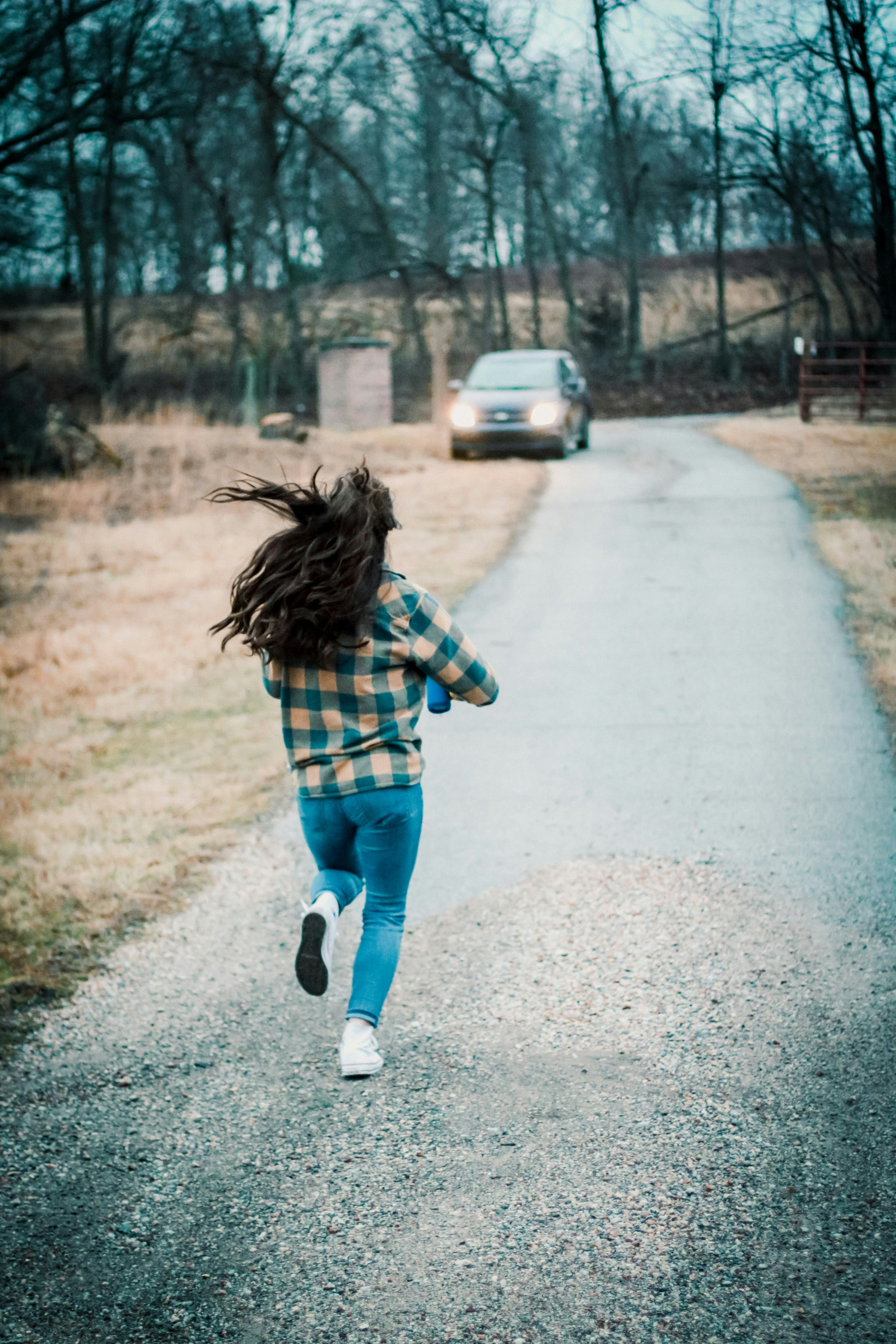 girl in blue denim shorts walking on gray asphalt road during daytime