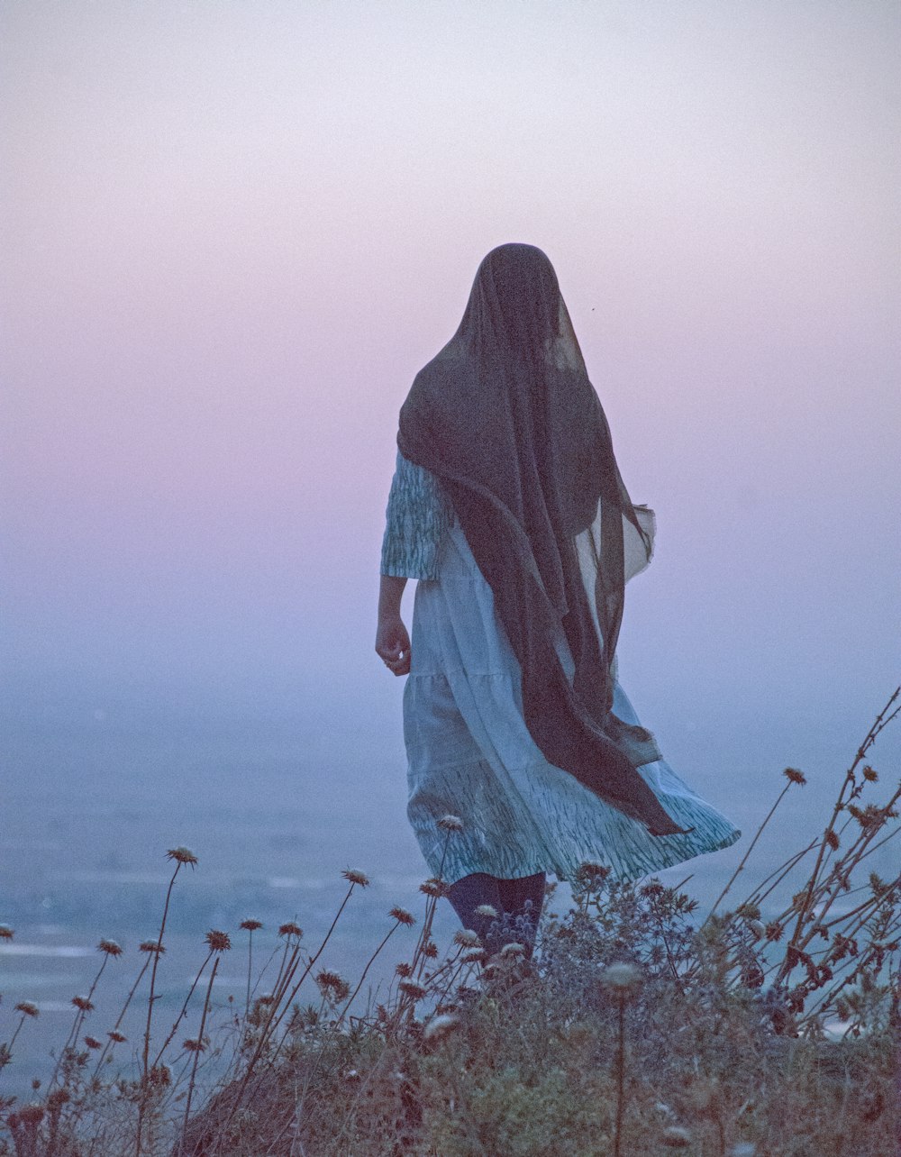 woman in blue hijab standing on brown dried leaves during daytime