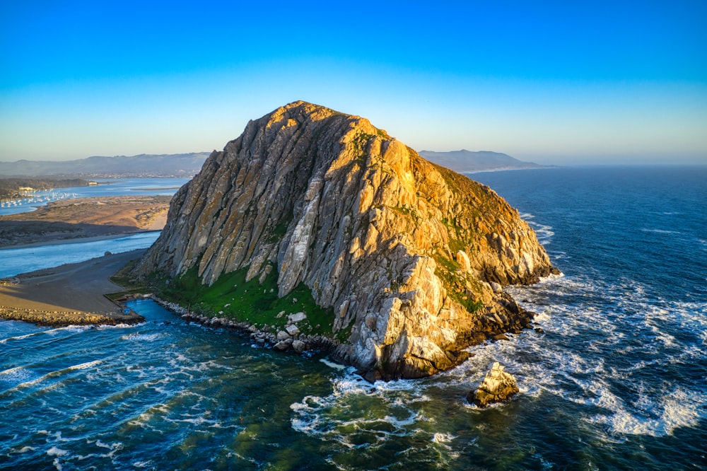 formación rocosa verde y marrón en el mar azul bajo el cielo azul durante el día