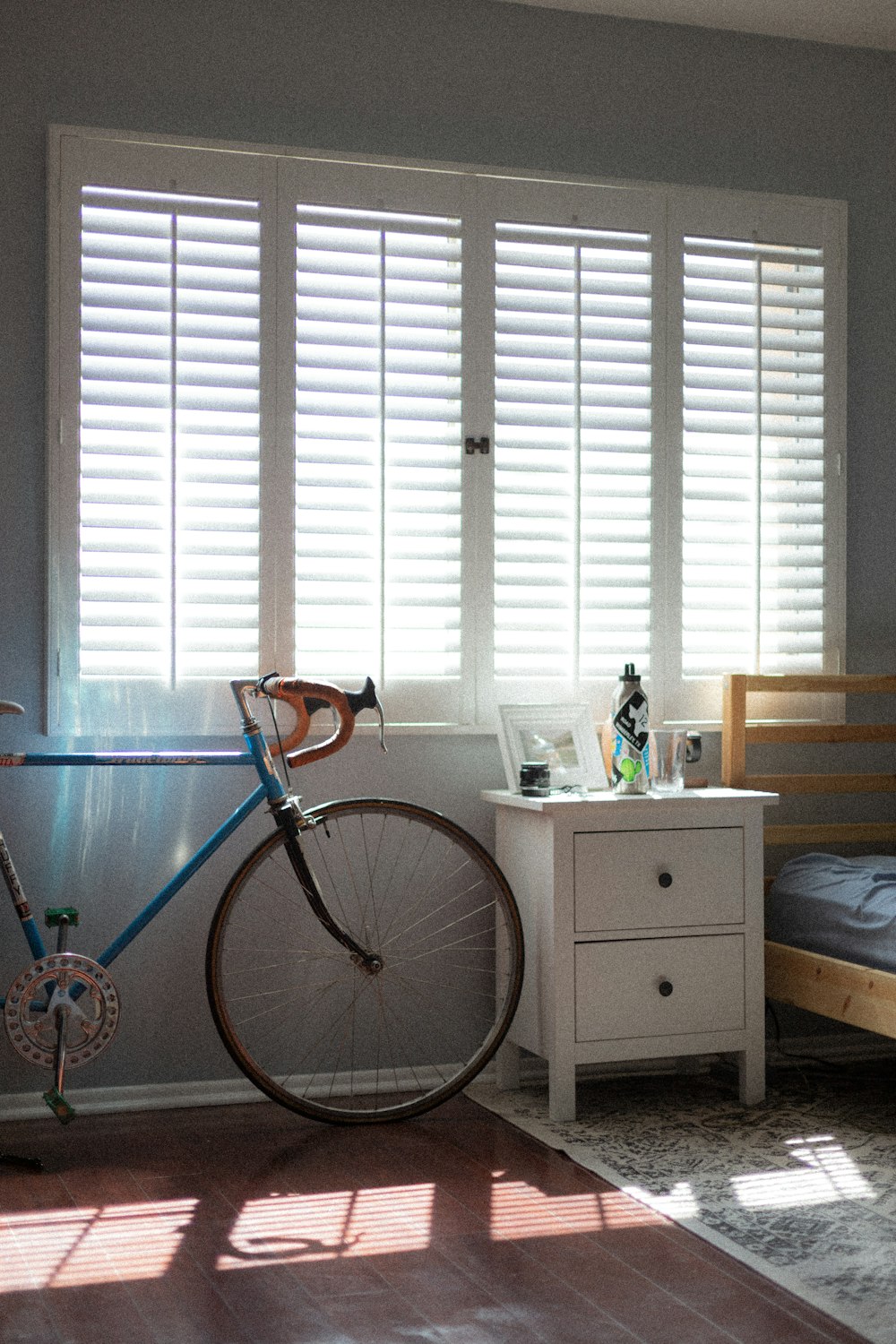 blue and black bicycle beside white wooden drawer