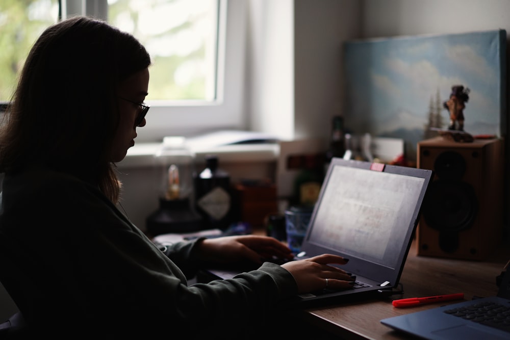 woman in black jacket using macbook pro