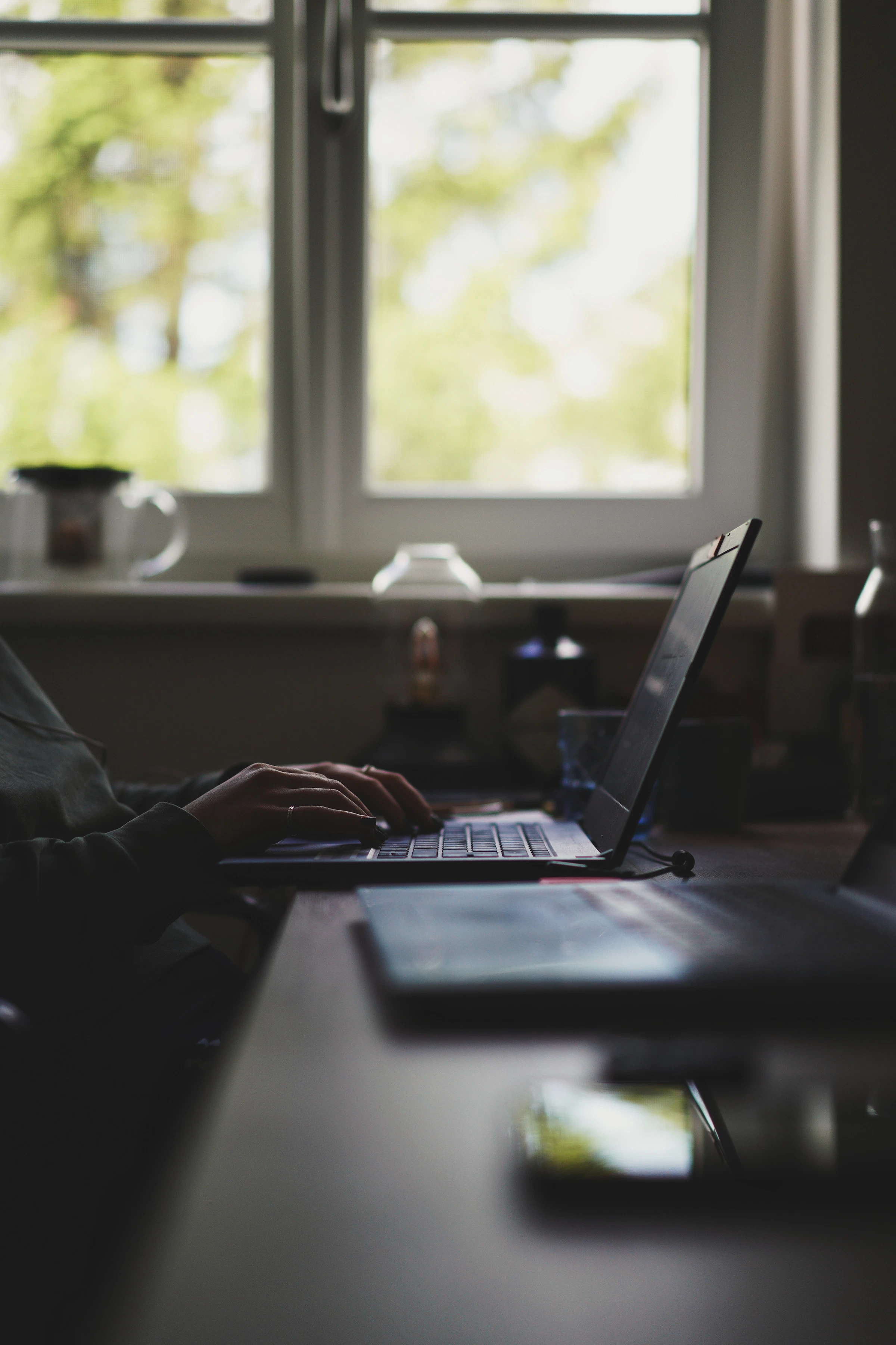 Professional working on a laptop beside a bright window during an extended stay